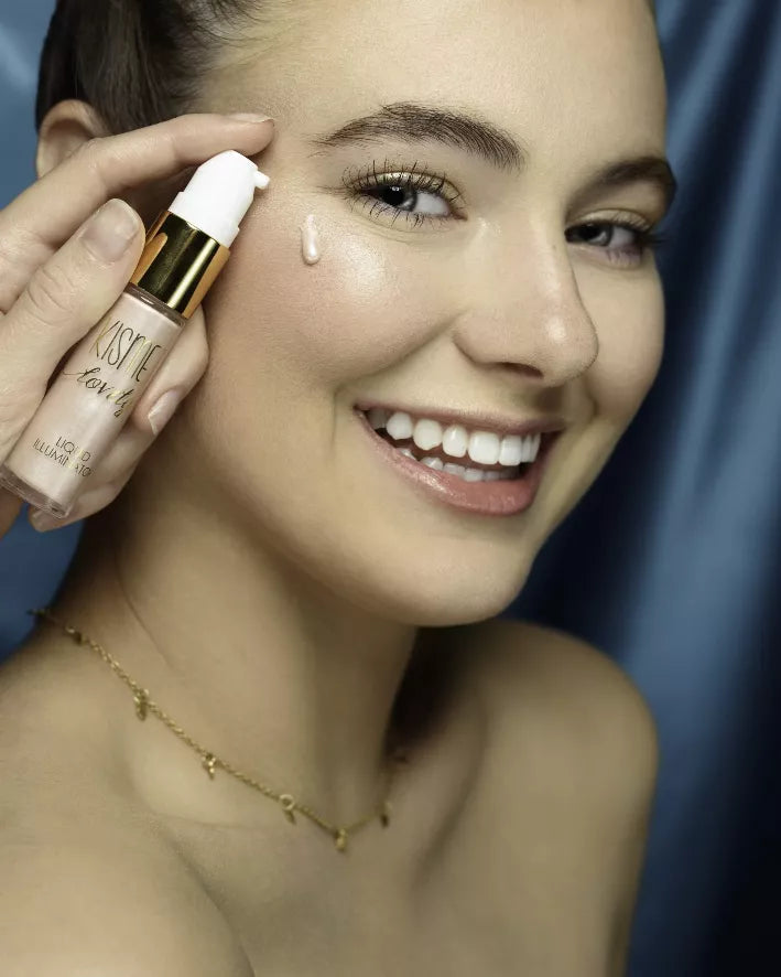 Woman applying liquid illuminator from bottle, drop on cheek, smiling