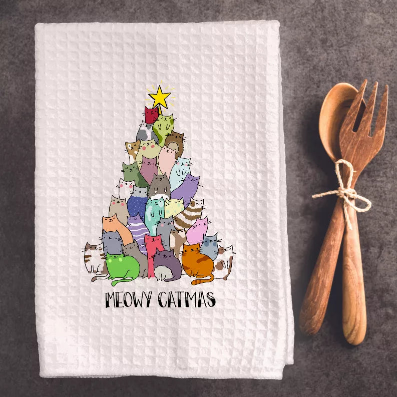 White waffle-weave tea towel with colorful cartoon cats and 'MEOWY CATMAS' text