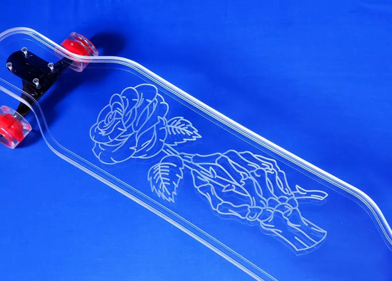 Close-up view of clear skateboard deck with skeleton rose graphic and red wheels
