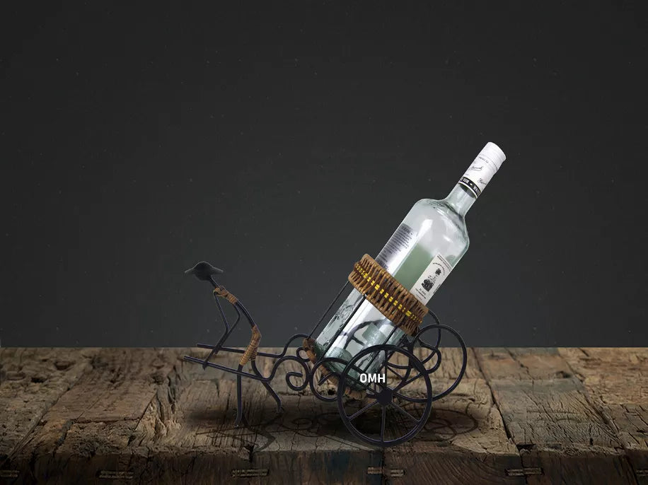 Rickshaw wine bottle holder with clear bottle, wicker basket, and black metal wheels