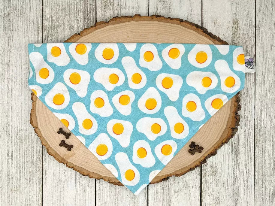 Light blue dog bandana with yellow egg pattern, no-tie triangle bib