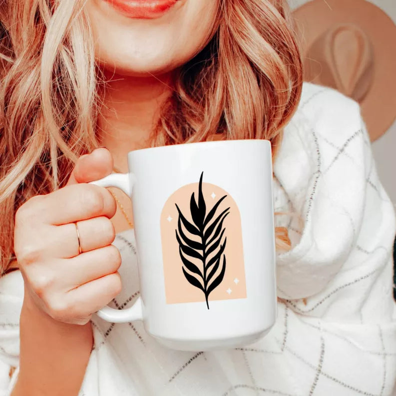 White ceramic coffee mug with black leafy branch design on front