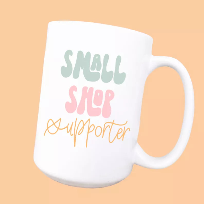White ceramic coffee mug with “Small shop supporter” colorful lettering and handle