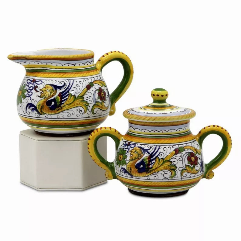 Decorative ceramic creamer and lidded sugar bowl with green handles and blue floral trim