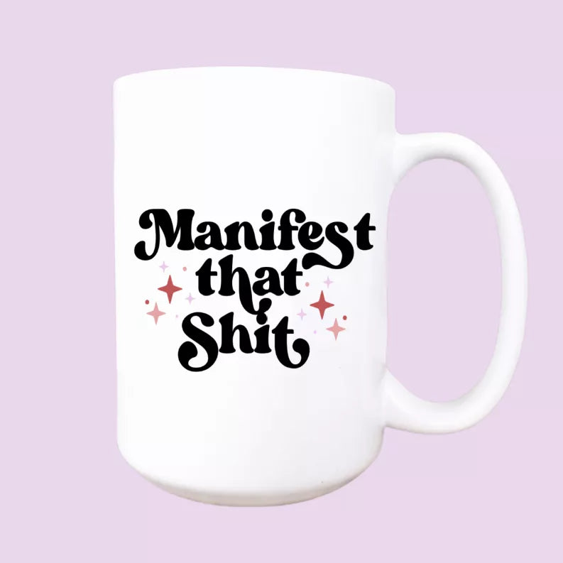 White ceramic coffee mug with 'Manifest that Shit' lettering and stars