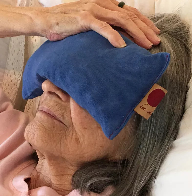 Blue fabric eye pillow with stitched edges and small fabric tag on side.