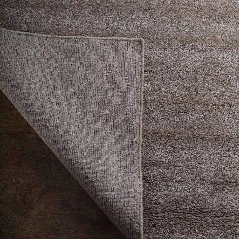 Side view of medium gray rug showing thickness and overlocked edge binding