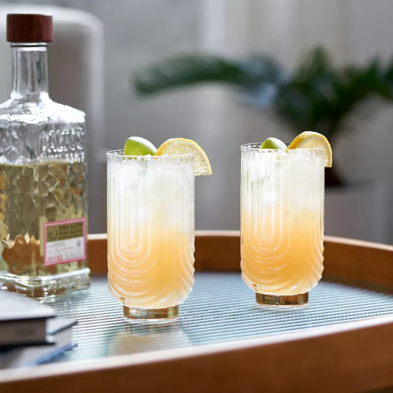 Gold-tinted highball glasses with lemon and ice, two clear tumblers
