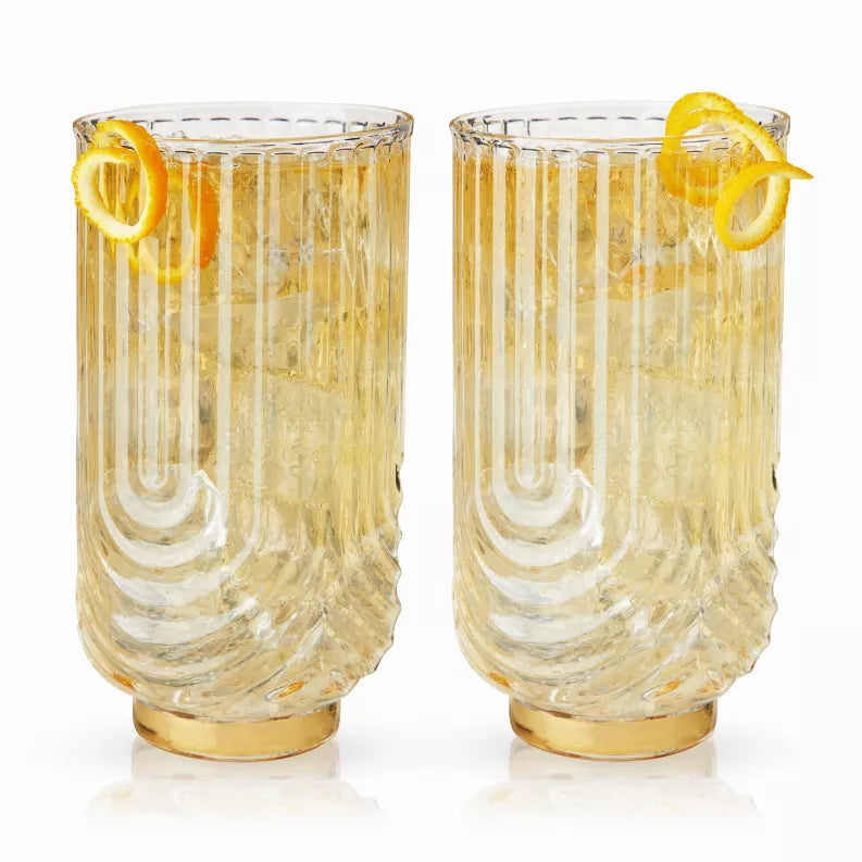 Pair of gold-tinted highball glasses with curved draping lines and citrus garnish