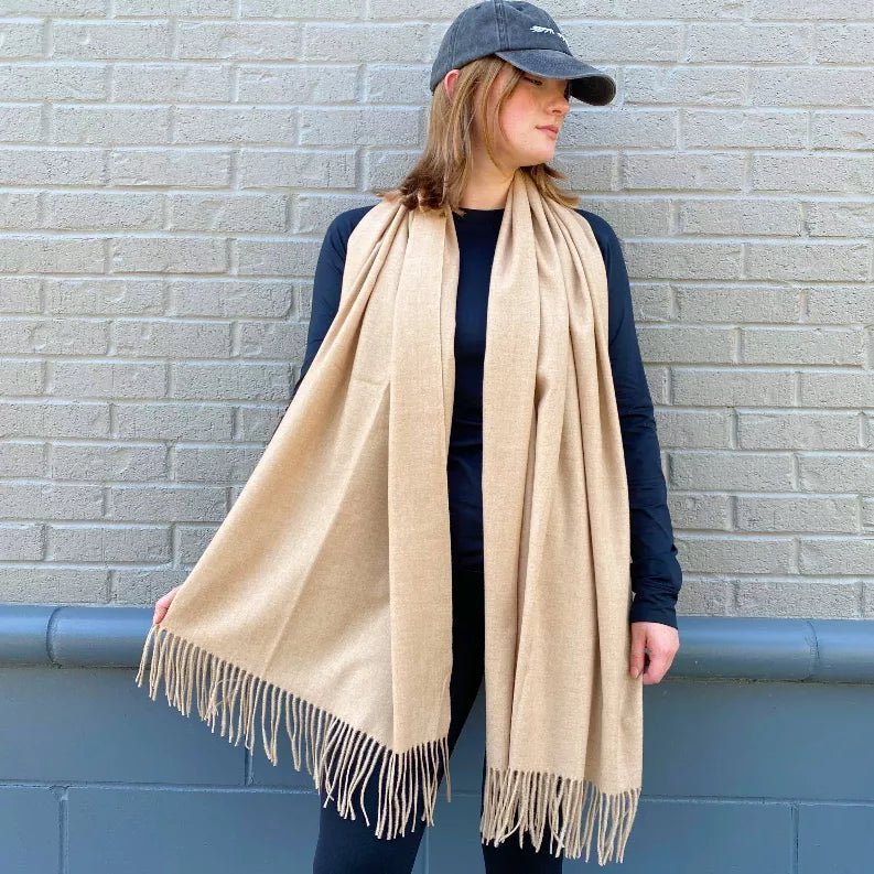 Heather beige cashmere blend scarf with long fringes, draped over shoulders