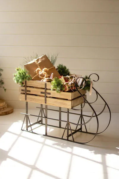 Brown wooden Christmas sled with metal runners, garland and wrapped gift decorations