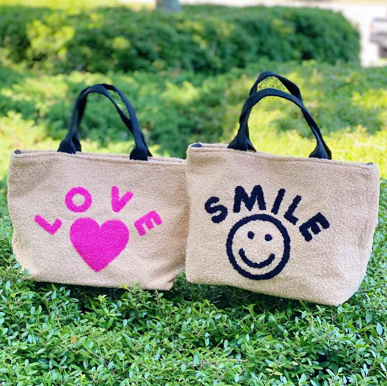 Set of two beige cross-body totes with smiley and heart text graphics