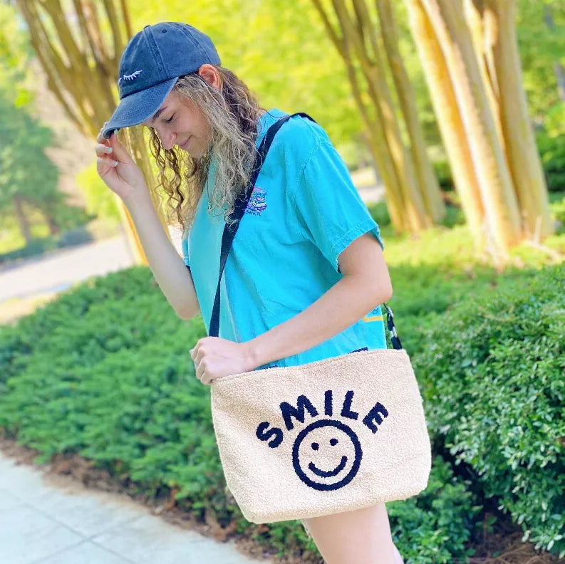 Beige cross-body tote bag with blue 'SMILE' smiley face logo