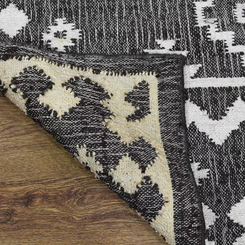 Kilim rug corner detail with diamond pattern in black, ivory, and beige highlights.