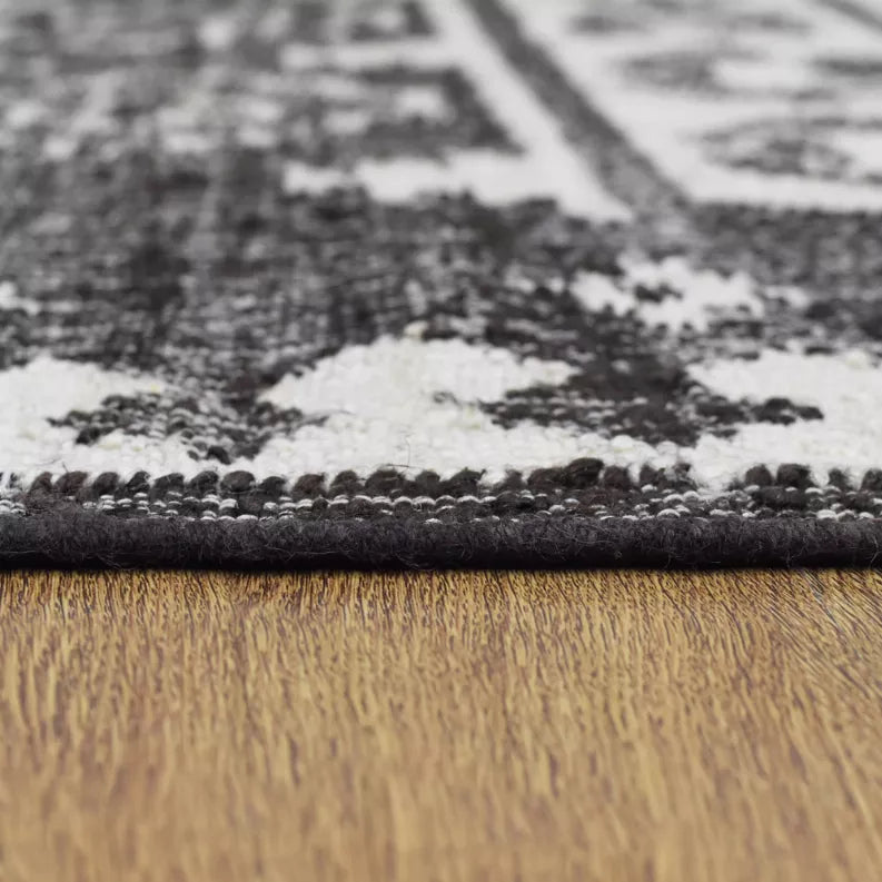 Kilim rug edge with stitched border and high-contrast black-and-ivory design.