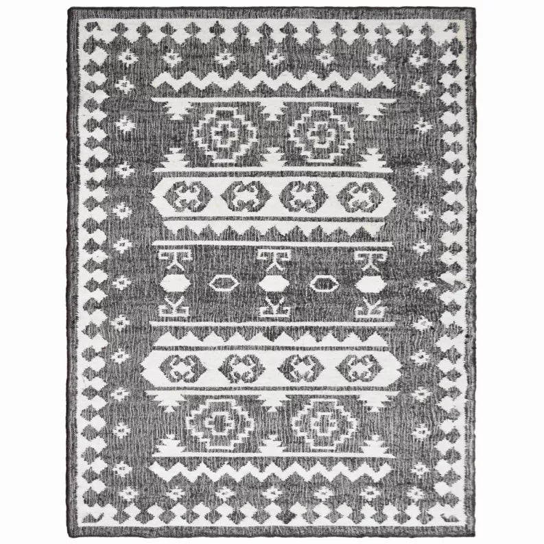 Geometric kilim area rug with centered medallions in dark gray and white tones.