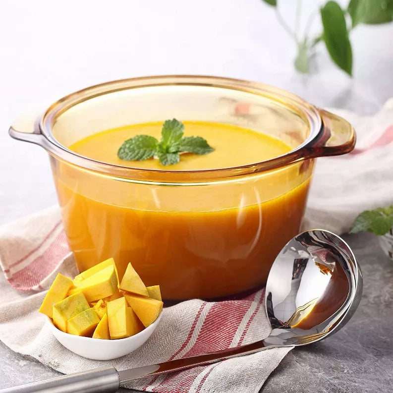 Stainless steel ladle and serving spoon over a pot of soup