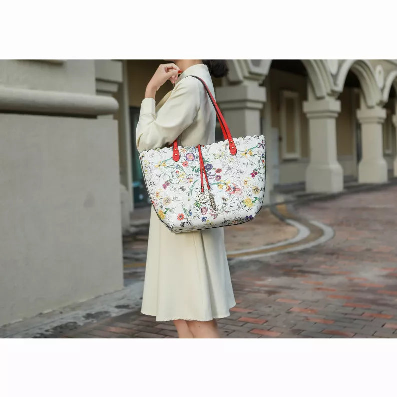 White floral reversible tote bag with red handles, held over the shoulder