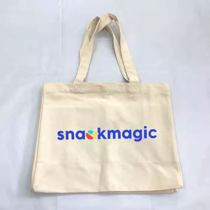 Reusable cotton tote bag with handles, front logo text 'snackmagic', beige