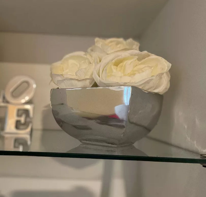 Decorative flower vase with cream faux flowers in a chrome round bowl