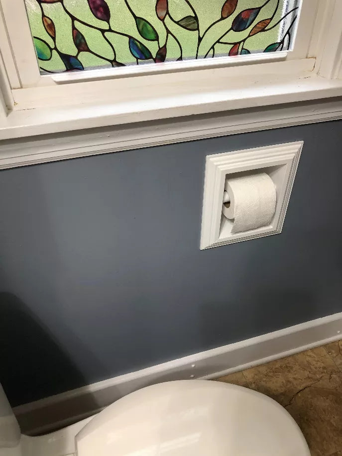 Recessed solid wood toilet paper holder installed on a wall with a white paper roll.