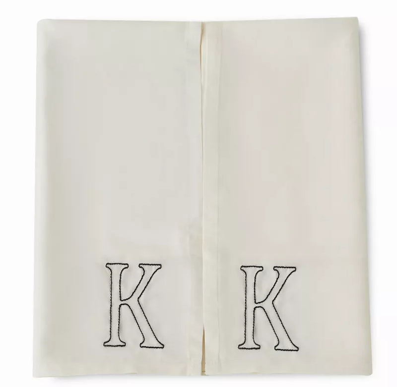 Ivory pillowcases with embroidered K crests, folded together