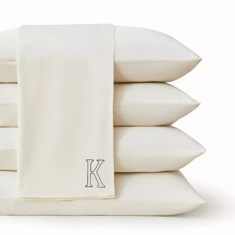 Ivory fitted sheet with embroidered K crest on front edge, folded