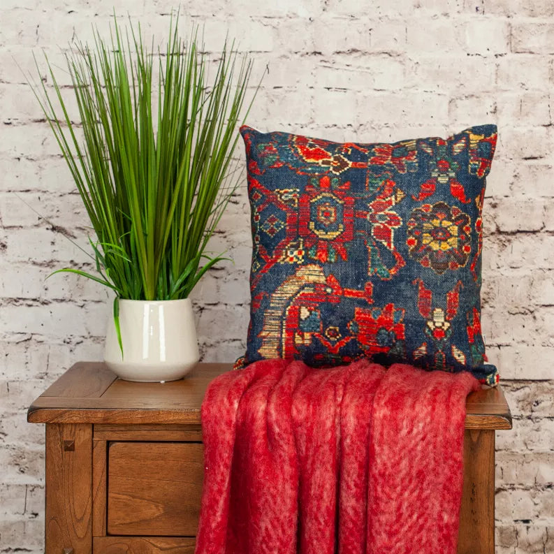 Square tapestry pillow with navy blue, red, and gold geometric pattern on the front