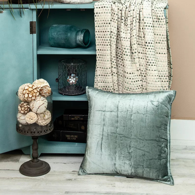 Sea foam quilted throw pillow, square 20 x 20 in, on a sofa with side decor.
