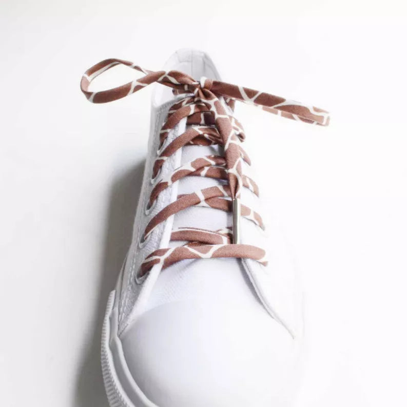 Brown and white animal print shoelaces on a white sneaker with metal aglets