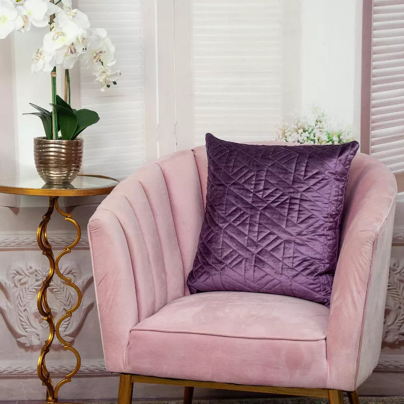Purple quilted throw pillow on a pink upholstered armchair