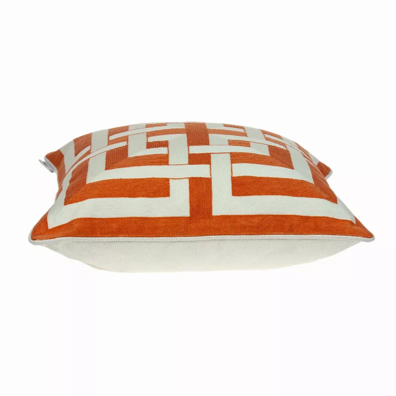 Orange and white geometric patterned throw pillow with piped edges