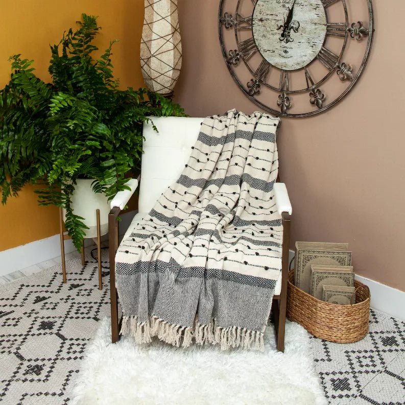 Woven handloom throw on chair, striped zigzag and dot motifs in cream and dark gray