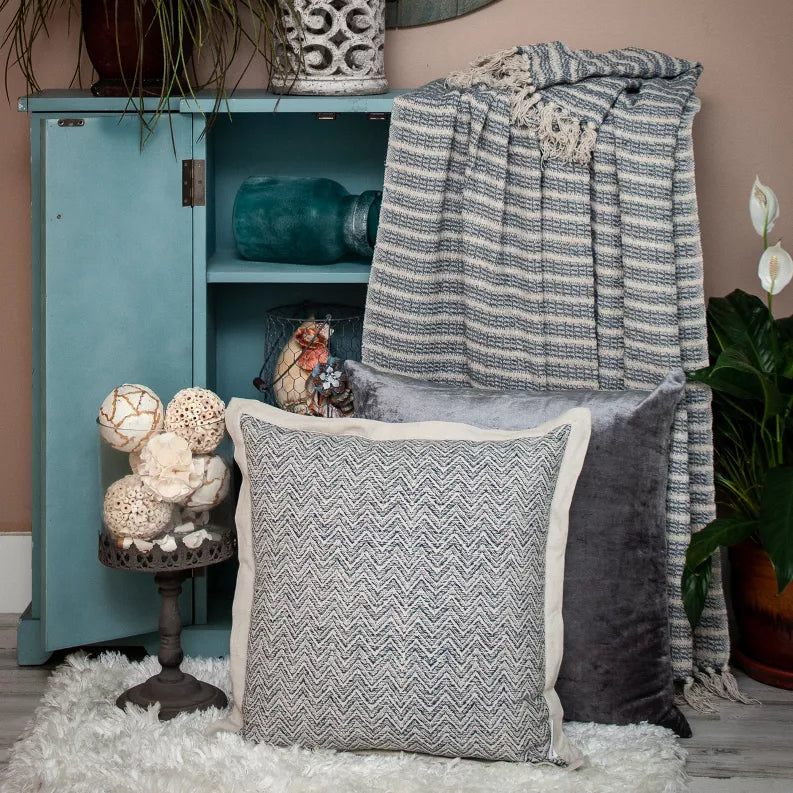 Woven throw blanket with blue-and-cream striped weave and long fringe, draped