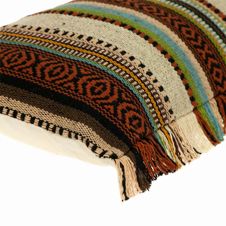 Corner detail of a striped woven throw pillow with fringed tassels