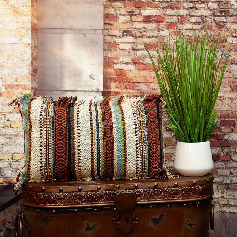 Multicolor striped throw pillow with fringed ends on a wooden bench