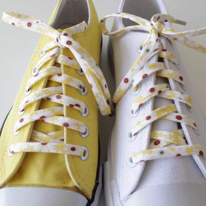 Floral-pattern shoelaces tied on yellow and white sneakers with bow