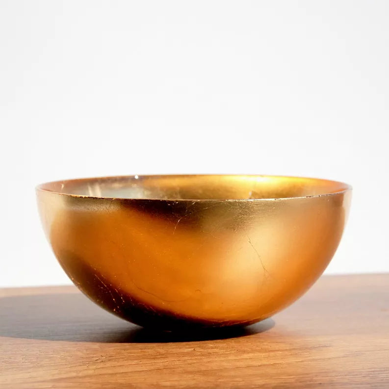 Gold glass serve bowl with rounded sides and reflective interior surface