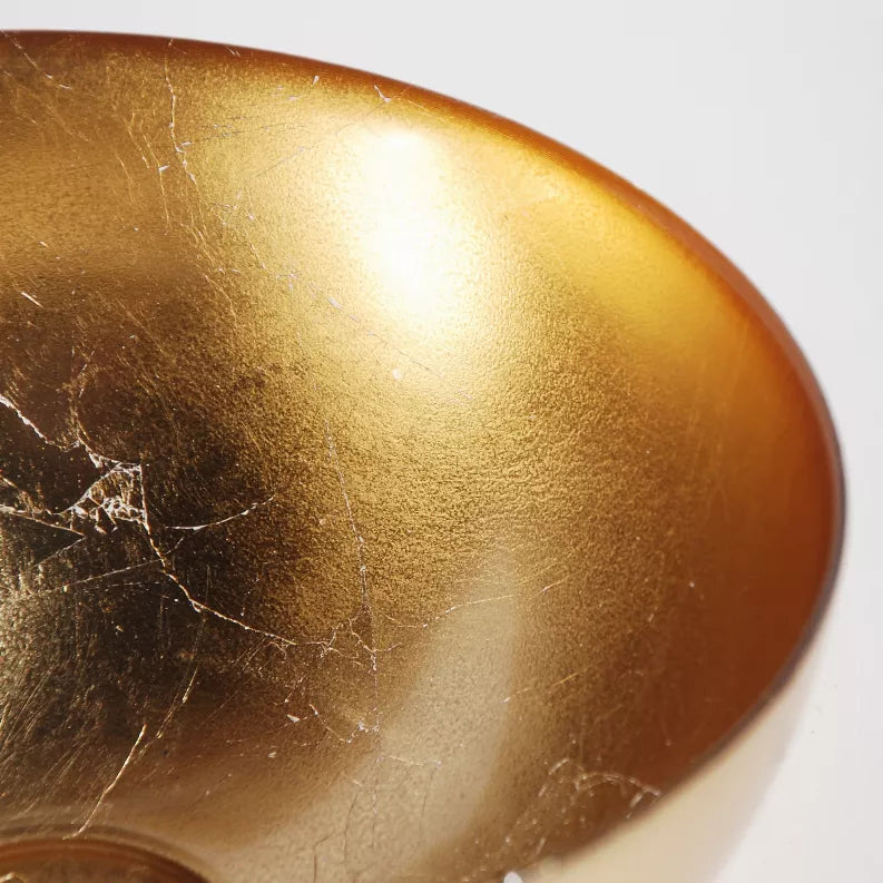 Gold glass bowl close-up with reflective surface and fine scratches