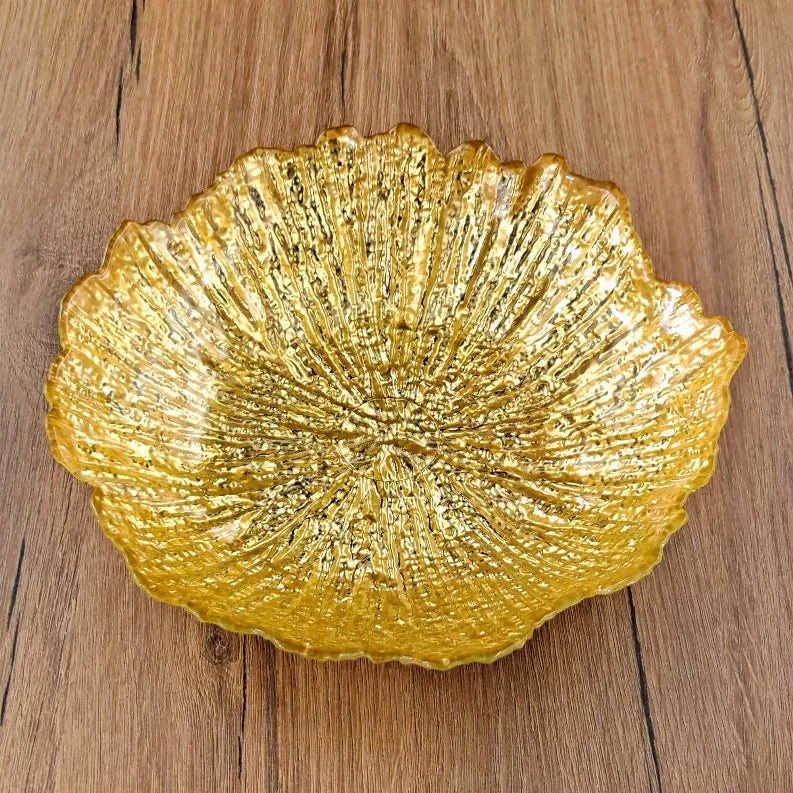 Gilded glass soup plate in gold tone on wood, scalloped rim and radiant ridges