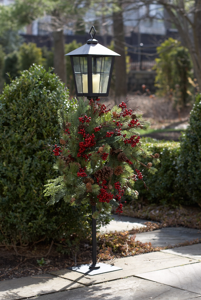 Metal lantern wreath holder with glass lantern top and decorated wreath on stake