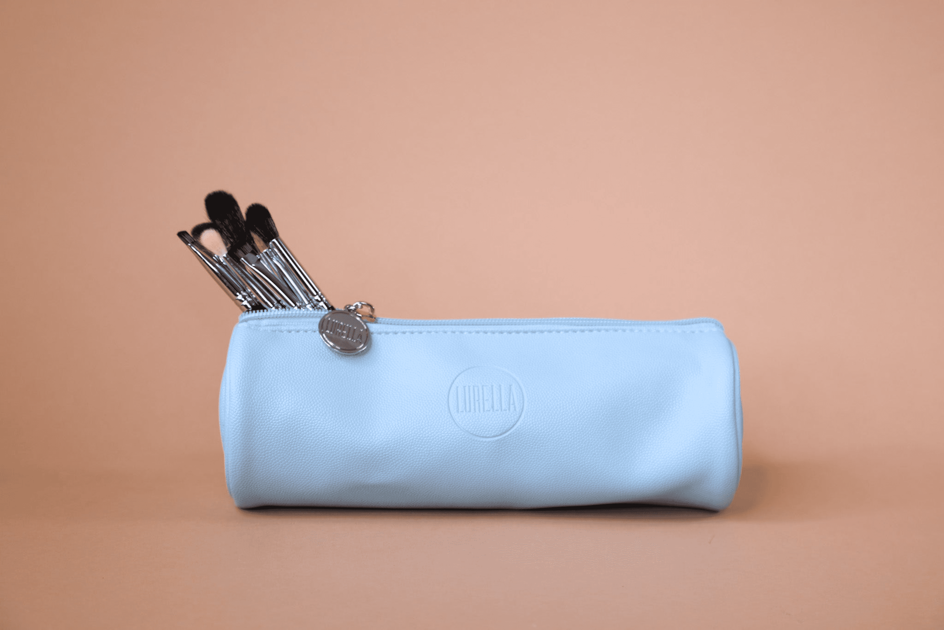 Light blue zippered brush bag with makeup brushes peeking from the top