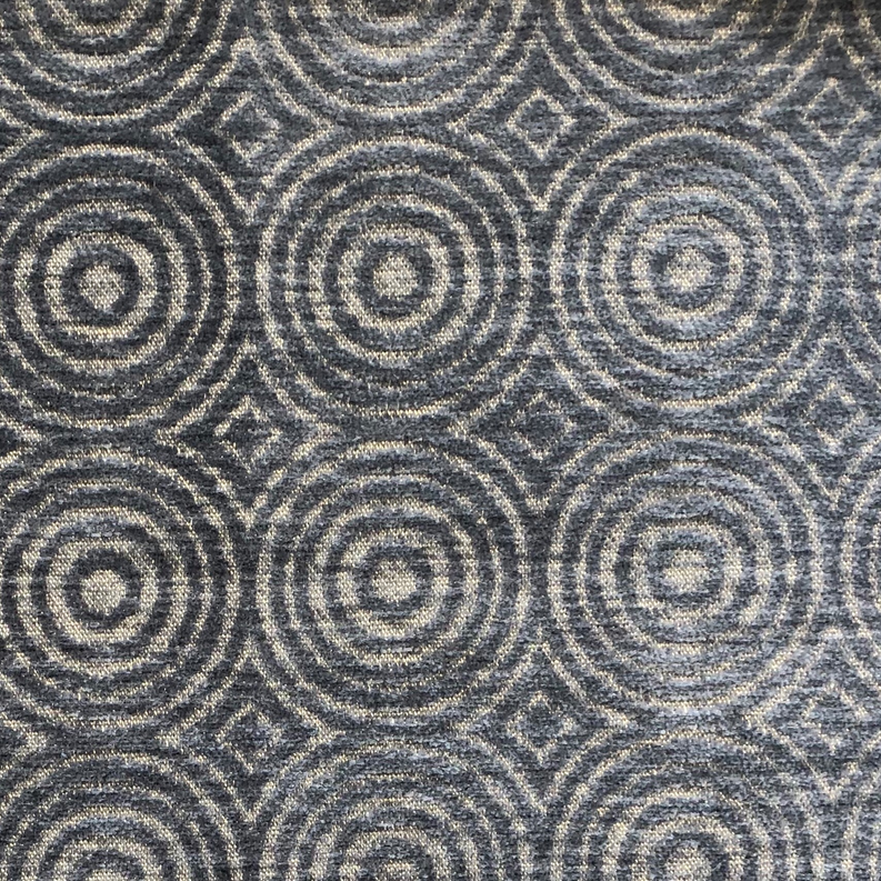 Close-up of blue-gray fabric with repeating concentric circles and diamond grid