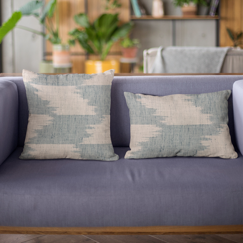 Two blue and beige abstract throw pillows on a sofa