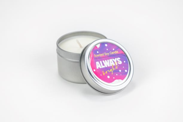 Scented soy candle in gray tin with open lid showing white wax and label