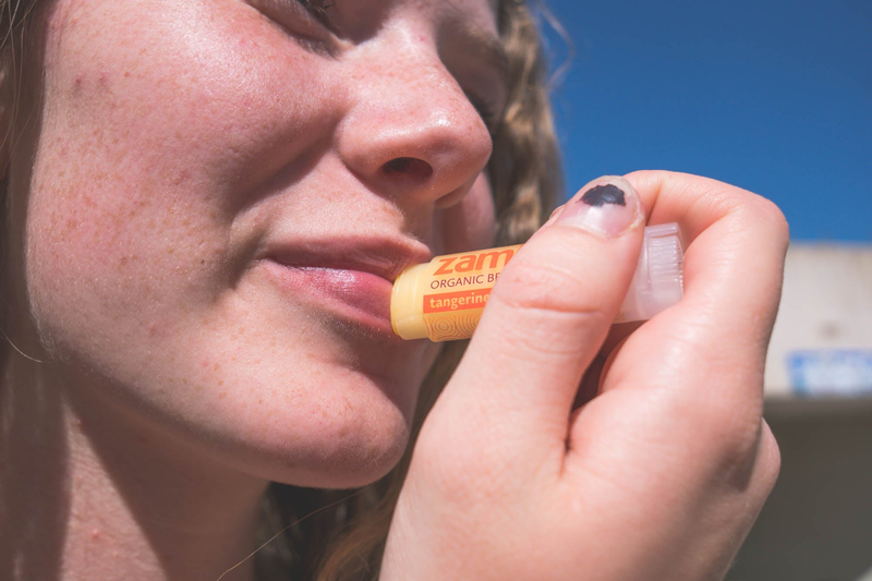 Organic beeswax lip balm in tangerine flavor from clear tube, applied to lips