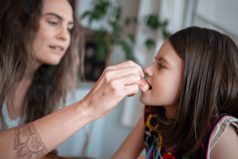 Lip balm stick being applied to a child’s lips by hand