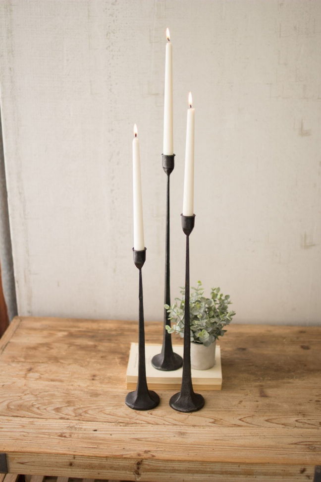 Set of three tall black cast iron taper candle holders with candles