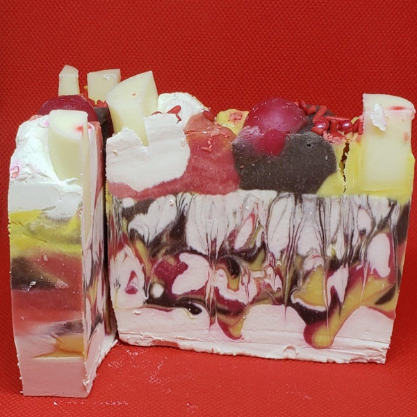 Banana split cream soap bar, layered red, yellow, white, and dark chunks on top