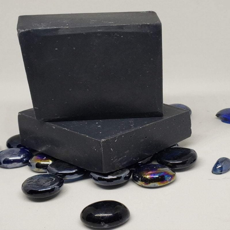 Activated charcoal soap bars in dark color, stacked smooth rectangular bars.
